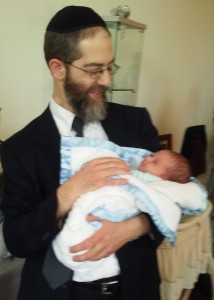 Rabbi Hamaoui gently holding a newborn
