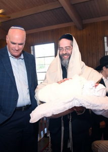Rabbi Hamaoui holding a baby during a ceremony